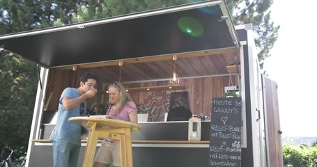 Young adult couple eating outside at food truck at music festival