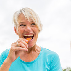 mature woman bites in a carrot