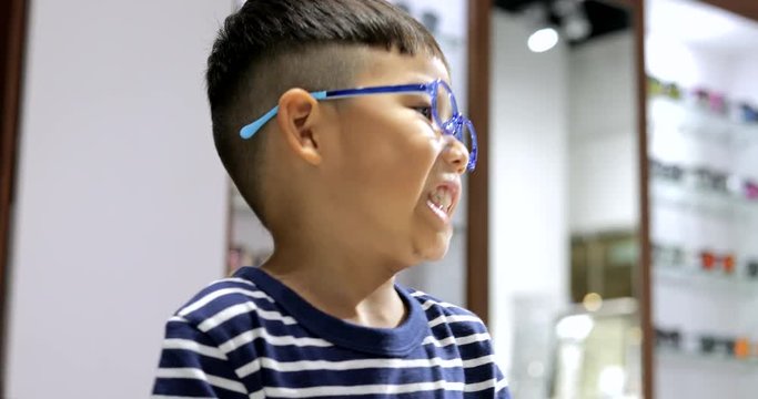 Asian Little boy trying glasses in optical shop