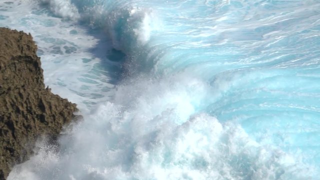 SLOW MOTION CLOSE UP: Huge turbulent foamy ocean wave breaking. Perfect barrel wave rolling upon the shore splashing. Big powerful swell wave crushing over the sharp rocky reef spraying sea waterdrops