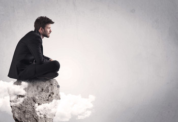 Office worker sitting on top of a rock