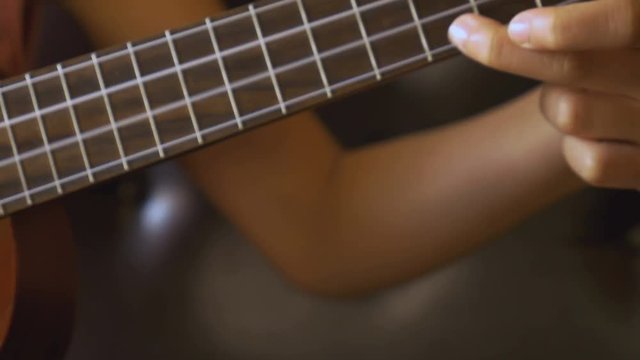 4K Video : Little Asian child playing ukulele on sofa, Pan shot