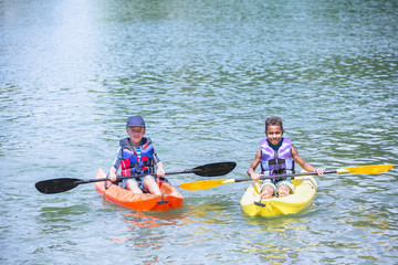 	Two diverse boys kayaking together on the lake 