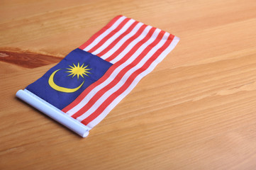 Malaysian flag lay flat on top of wooden table.