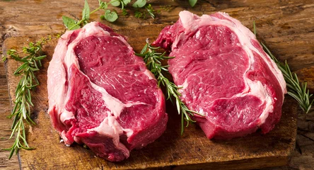 Fotobehang Raw meat Ribeye Steak with seasoning  on dark wooden background © bit24