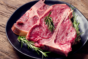 Raw fresh meat t-bone steak and seasoning on wooden background