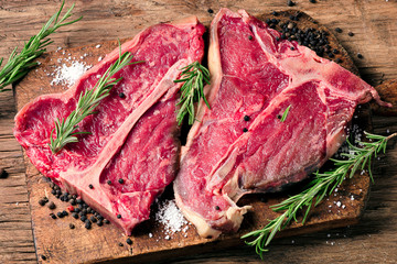 Raw fresh meat t-bone steak and seasoning on wooden background