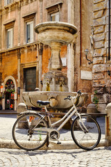 Old bicycle next to a fountain at a small square in central Rome
