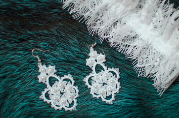 White lace bridal accessories on the fur blue background. Wedding garter on the texture background. fashion bridal earrings