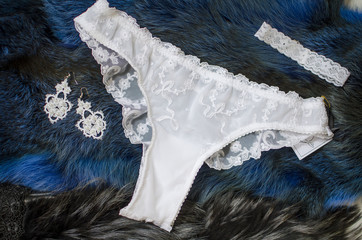 White bridal panties on the blue background with dried roses. Fashion wedding accessories and jewelry