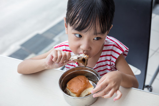 Asian Chinese little girl eating fried chicken