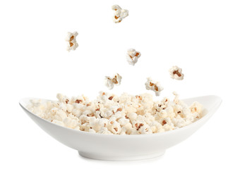 Tasty popcorn falling onto plate on white background