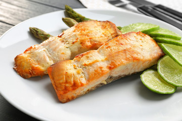 Tasty salmon with slices of lime and asparagus on plate