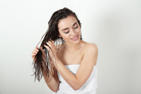 Young woman in towel after shower on white background