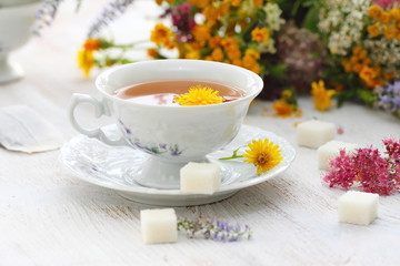 Obraz na płótnie Canvas Cup of herbal tea and flowers