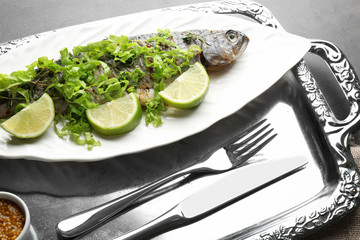 Plate with delicious fried fish on metal tray