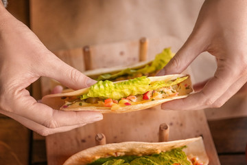 Woman eating delicious taco with fillet of fish and vegetables in restaurant
