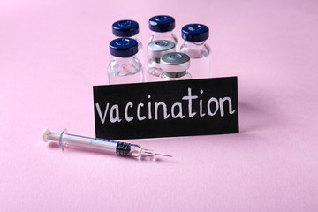 Card with word VACCINATION, ampules and syringe on color background