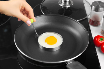 Hand of woman frying sunny side up egg in mold