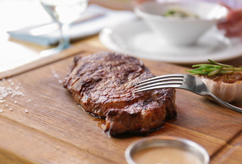Delicious grilled steak on wooden board in restaurant