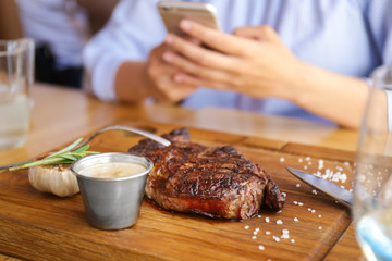 Delicious grilled steak on wooden board in restaurant