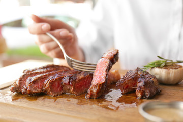 Young woman eating grilled steak in restaurant