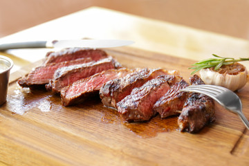 Delicious sliced steak on wooden board in restaurant