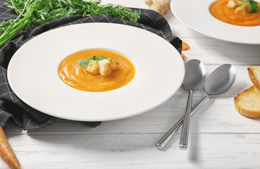 Plate with delicious carrot soup on table