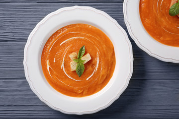 Plates with delicious carrot soup on wooden table