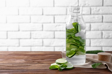 Delicious refreshing water with mint and cucumber in glass bottle on wooden table