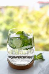 Delicious refreshing water with mint and cucumber in glass on table