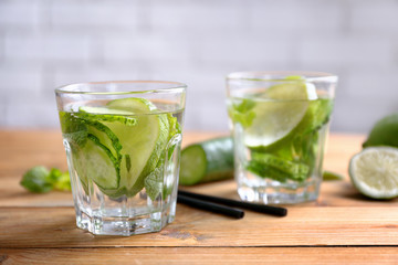 Delicious refreshing water with mint and cucumber in glasses on wooden table