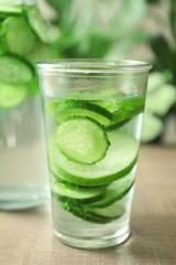 Delicious refreshing water with mint and cucumber in glass on wooden table