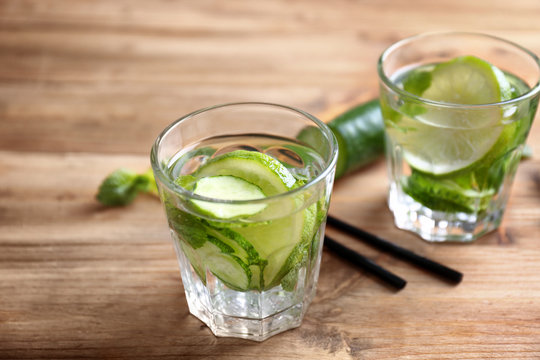 Delicious refreshing water with mint and cucumber in glasses on wooden table