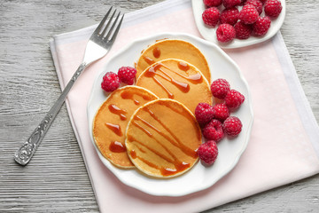 Plate with delicious pancakes on wooden background