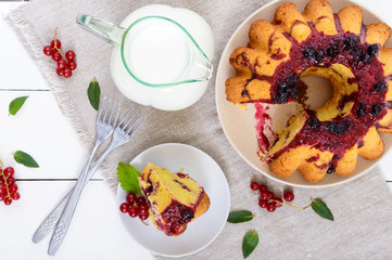 A large piece of cottage cheese cake with summer berries, jam  and a jug of milk on white background. The top view