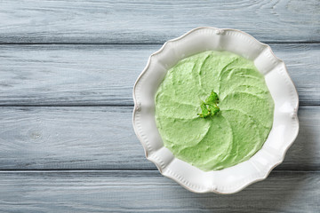Plate with delicious broccoli soup on wooden background