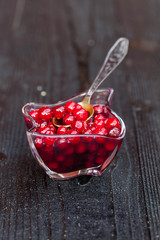 Cranberry sauce in glass on black rustic wooden background, soft focus