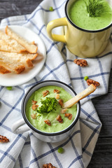 Delicious broccoli soup with walnut in mug on table