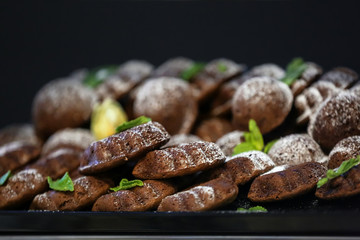 Many chocolate sponge cakes with powdered sugar, closeup