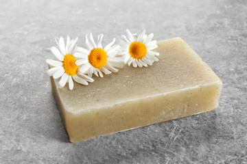 Soap and chamomile flowers on table