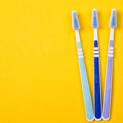 three Toothbrushes on yellow background