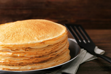 Stack of delicious thin pancakes on frying pan, closeup