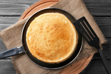 Stack of delicious thin pancakes on frying pan, top view