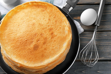 Stack of delicious thin pancakes on frying pan