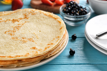 Thin pancakes with fresh berries on table