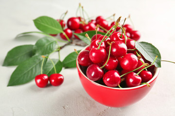 Obraz na płótnie Canvas Ripe cherries in red ceramic bowl on light background