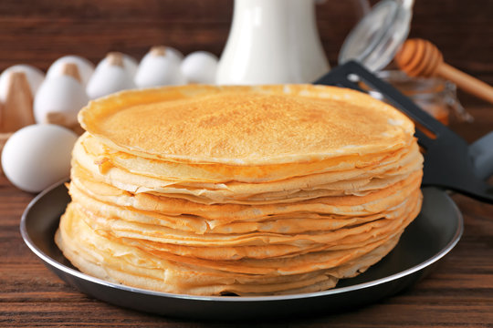 Stack of delicious thin pancakes on frying pan, closeup
