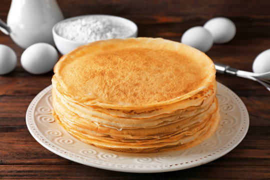 Stack of delicious thin pancakes on patterned white plate