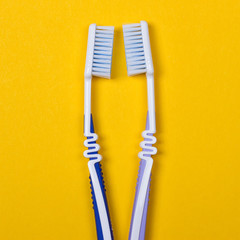 two Toothbrushes on yellow background